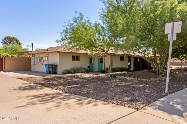 ranch-style house with fence, driveway, and brick siding