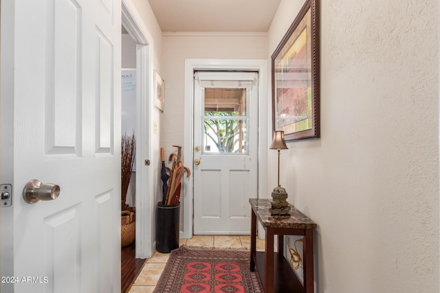 doorway featuring ornamental molding and light tile patterned floors
