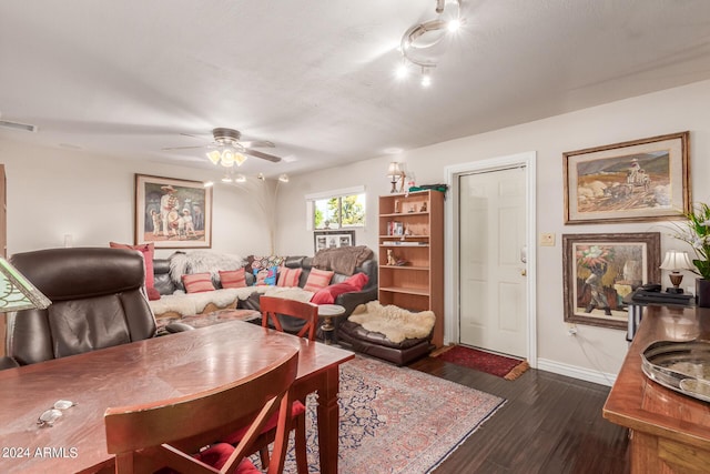 living area with dark wood finished floors, baseboards, visible vents, and ceiling fan