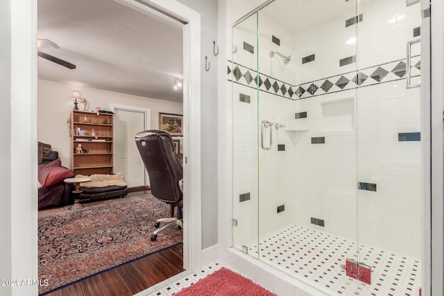 bathroom with connected bathroom, wood finished floors, and a stall shower