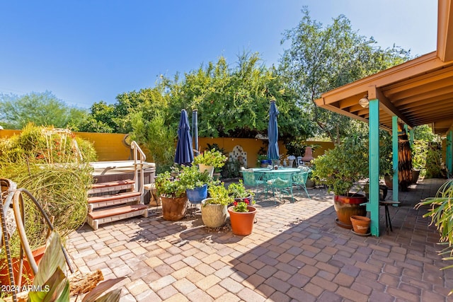 view of patio with a fenced backyard, a hot tub, and outdoor dining space