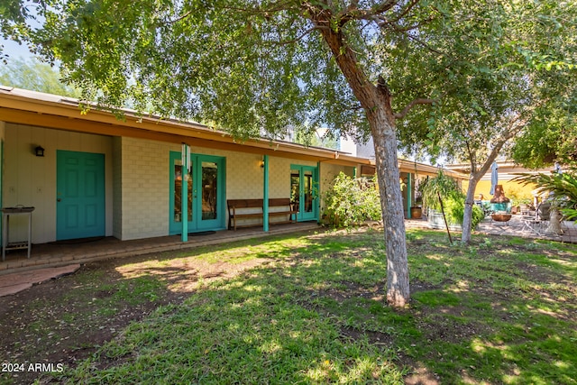 back of property with french doors and a lawn