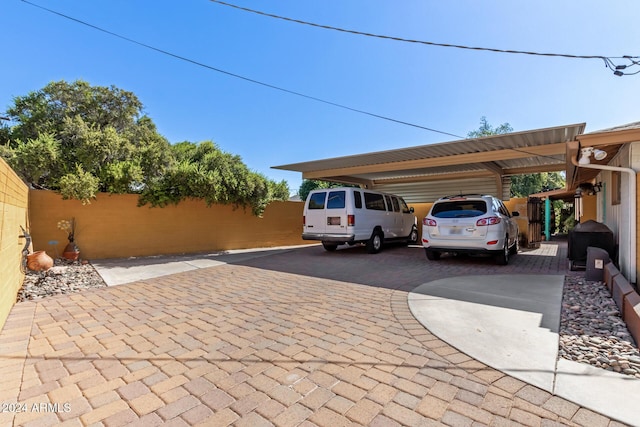 view of parking / parking lot with decorative driveway and fence