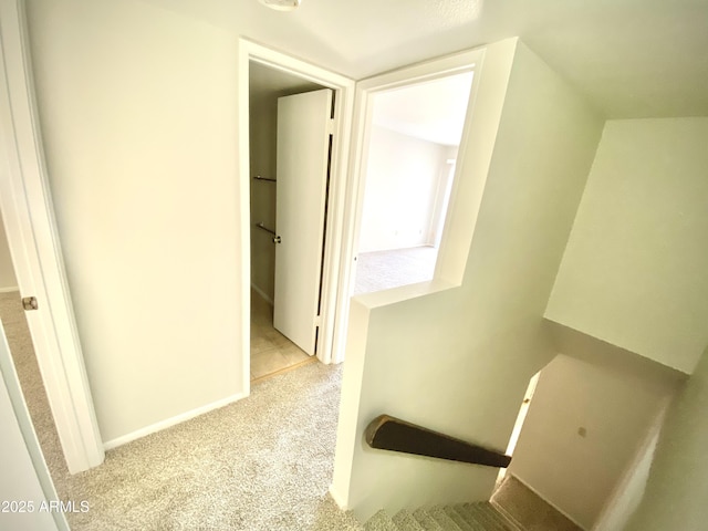 hallway featuring an upstairs landing, carpet, and baseboards