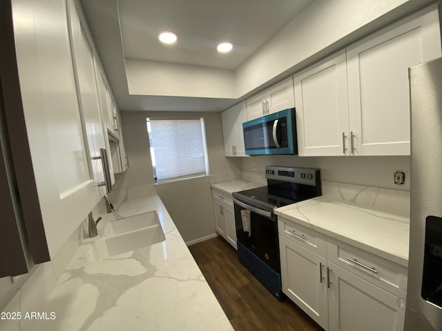 kitchen featuring dark wood-type flooring, range with electric stovetop, a sink, white cabinetry, and light stone countertops