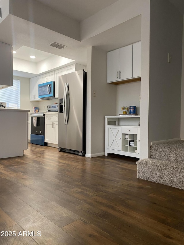 kitchen featuring a tray ceiling, dark wood finished floors, stainless steel refrigerator with ice dispenser, electric range oven, and white cabinets