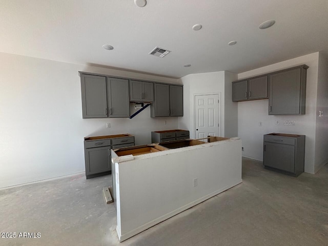 kitchen featuring unfinished concrete flooring, a center island, and gray cabinetry