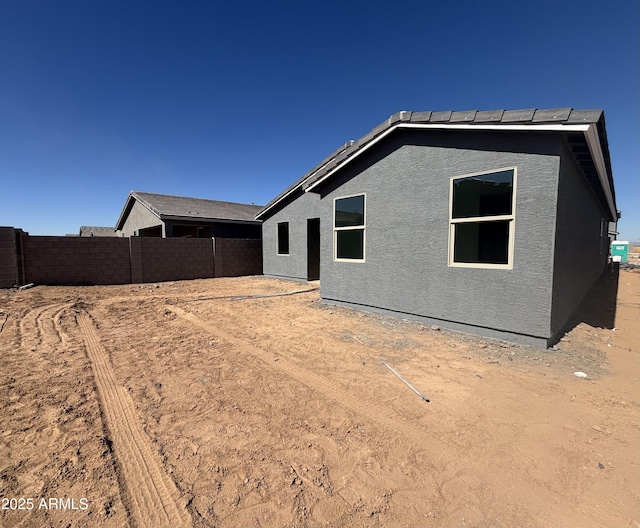 back of house with a fenced backyard and stucco siding