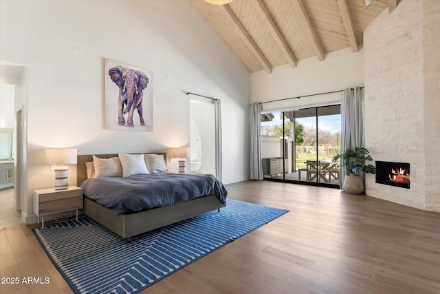 bedroom featuring wooden ceiling, wood finished floors, access to exterior, a fireplace, and high vaulted ceiling