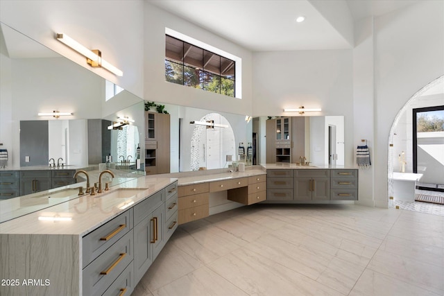 bathroom with marble finish floor, a high ceiling, a freestanding tub, and a sink