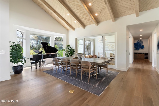 dining room featuring high vaulted ceiling, wood finished floors, wood ceiling, baseboards, and beam ceiling