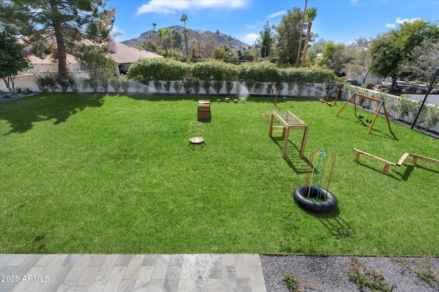 view of property's community with a mountain view, a lawn, and fence