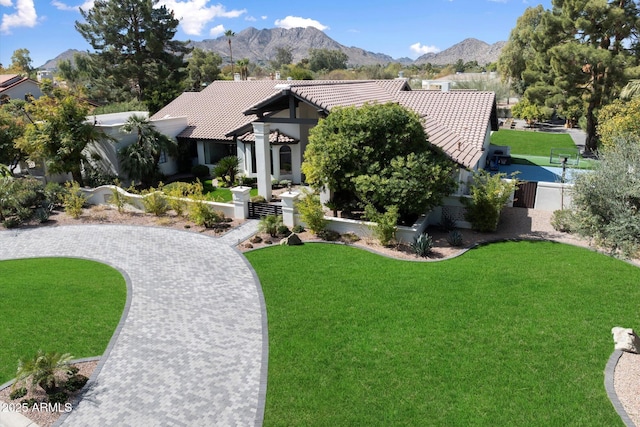 view of front of property featuring a front yard, a tile roof, and a mountain view