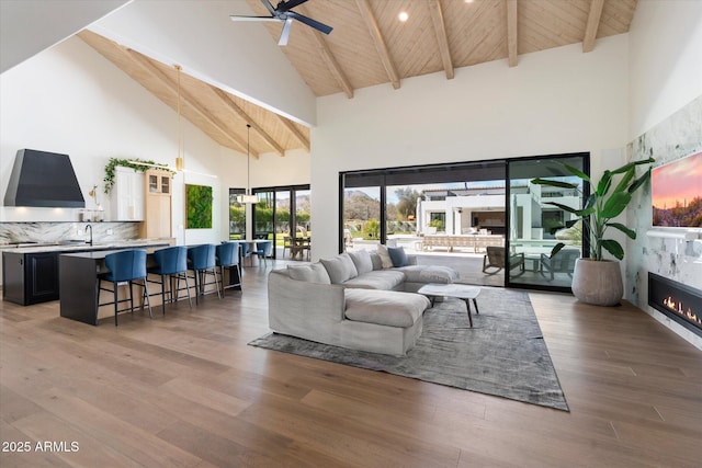 living area featuring light wood-type flooring, wooden ceiling, beam ceiling, and a high end fireplace