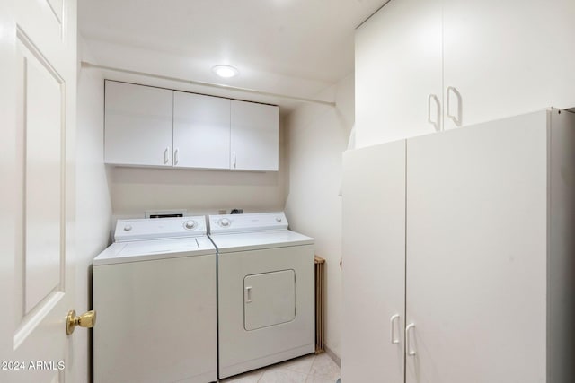 washroom with cabinets, light tile patterned floors, and washing machine and clothes dryer