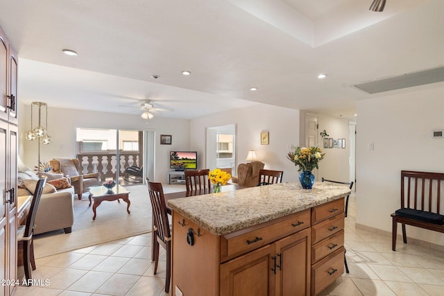 kitchen featuring a kitchen bar, ceiling fan, pendant lighting, light tile patterned floors, and a center island