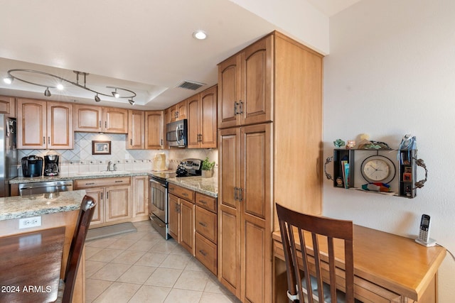 kitchen with light stone countertops, appliances with stainless steel finishes, tasteful backsplash, sink, and light tile patterned flooring