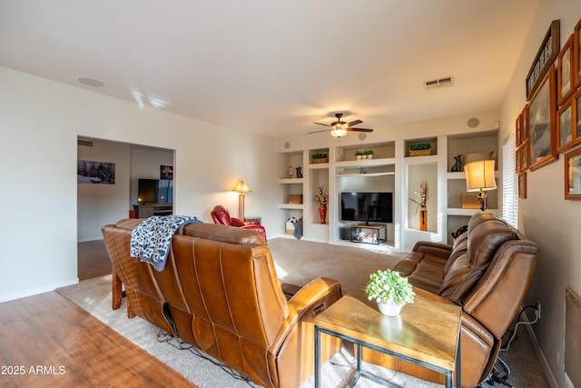 living area with baseboards, visible vents, a ceiling fan, wood finished floors, and built in shelves