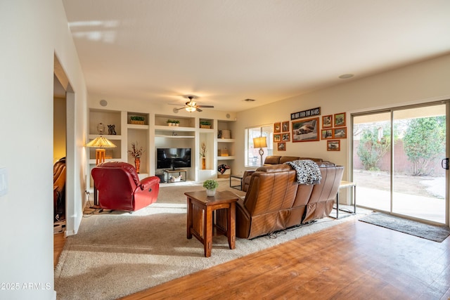 living area featuring built in features and a ceiling fan