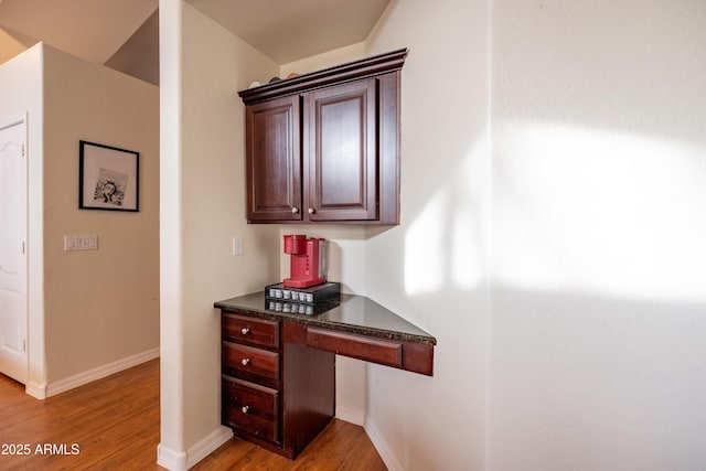 interior space with baseboards, built in desk, and light wood-style floors