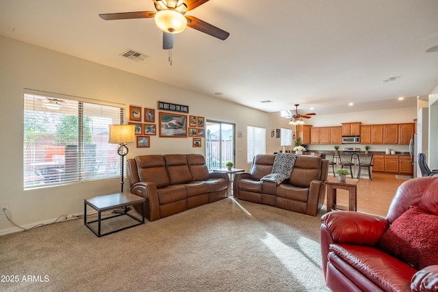 living area featuring ceiling fan, visible vents, and light colored carpet