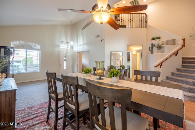 dining space with carpet, visible vents, stairway, high vaulted ceiling, and baseboards