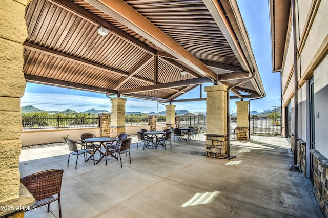 view of patio featuring outdoor dining area, fence, and a mountain view