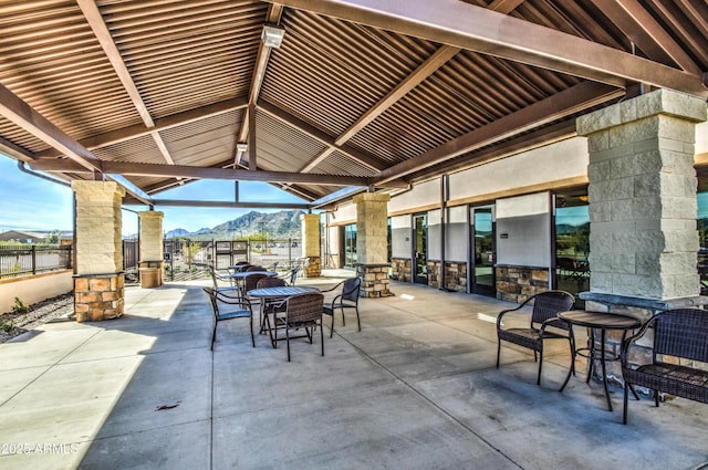 view of patio / terrace with outdoor dining space, a mountain view, and fence