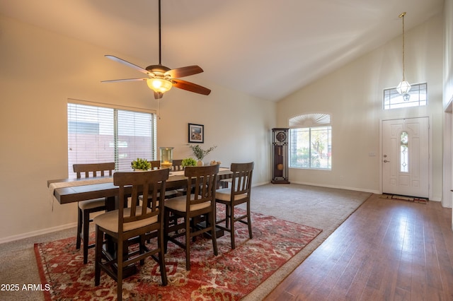 dining area featuring high vaulted ceiling, a ceiling fan, hardwood / wood-style flooring, and baseboards