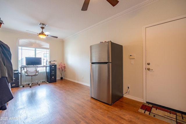 home office featuring baseboards, visible vents, a ceiling fan, wood finished floors, and crown molding