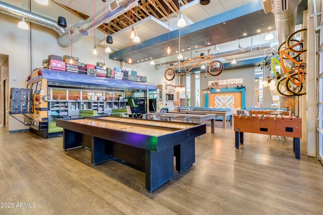 game room featuring wood-type flooring, a towering ceiling, and billiards