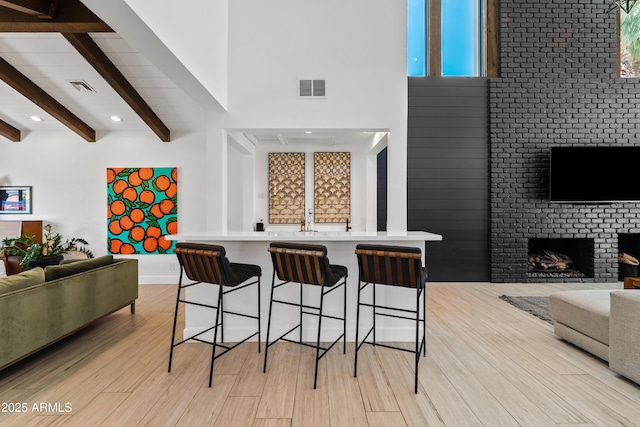 101 E Linger Ln, Phoenix, AZ 85020 - kitchen with open floor plan, beam ceiling, a towering ceiling, a breakfast bar area, and light wood-style flooring