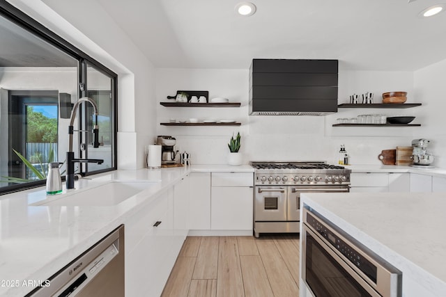 101 E Linger Ln, Phoenix, AZ 85020 - kitchen featuring open shelves, stainless steel appliances, wall chimney range hood, white cabinetry, and a sink