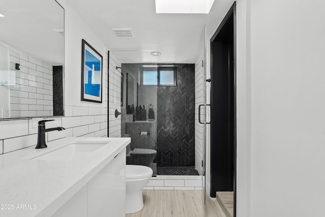 101 E Linger Ln, Phoenix, AZ 85020 - bathroom with tile walls, a shower stall, toilet, wood finished floors, and vanity
