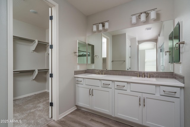 bathroom with double vanity, a spacious closet, visible vents, and a sink