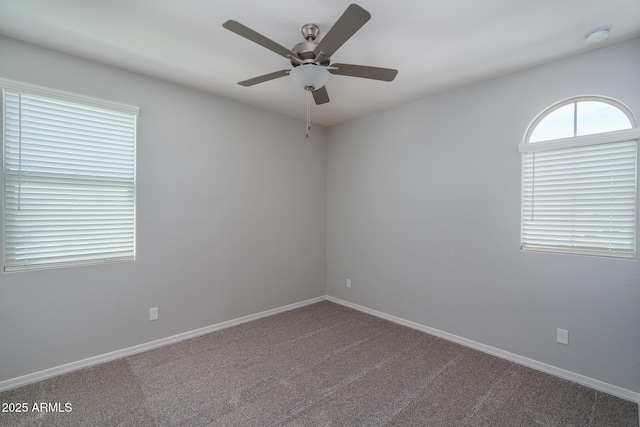 carpeted spare room with ceiling fan and baseboards