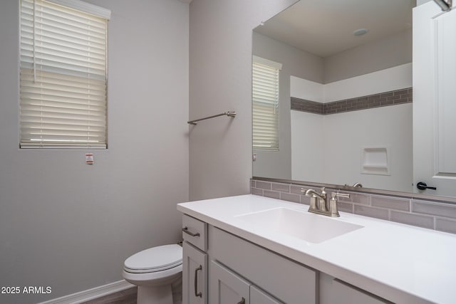 bathroom featuring backsplash, baseboards, vanity, and toilet