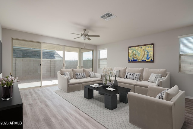 living room featuring visible vents, ceiling fan, and light wood finished floors