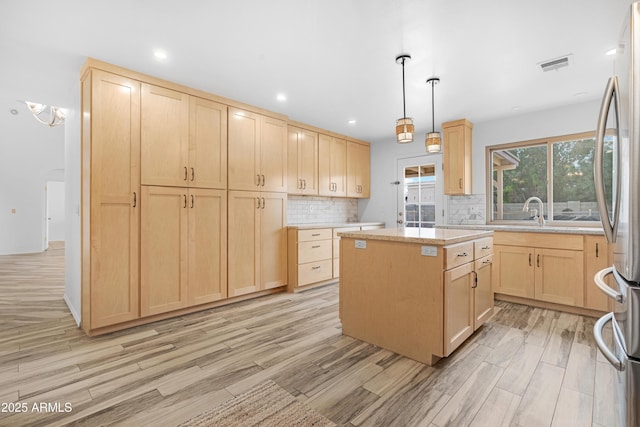 kitchen featuring decorative light fixtures, light brown cabinetry, and a kitchen island