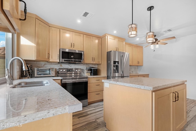 kitchen featuring appliances with stainless steel finishes, light brown cabinetry, sink, backsplash, and light hardwood / wood-style flooring