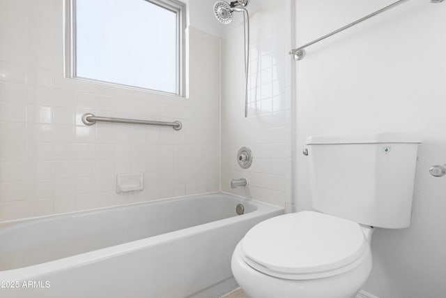 bathroom featuring tiled shower / bath combo and toilet