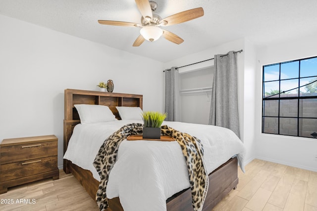 bedroom with ceiling fan, a textured ceiling, and light wood-type flooring