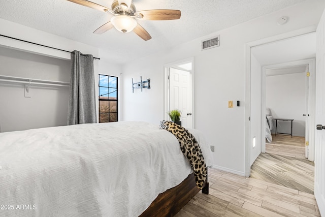 bedroom featuring ceiling fan, a textured ceiling, and light wood-type flooring