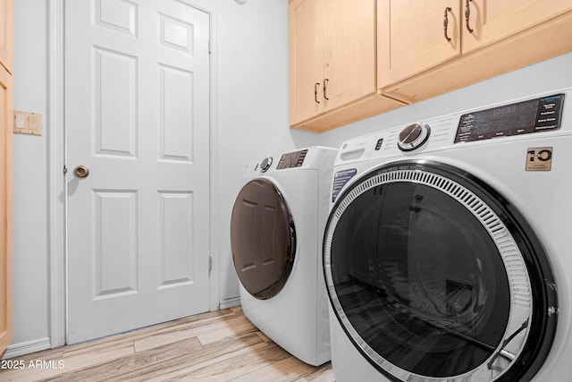 washroom with light hardwood / wood-style flooring, washer and clothes dryer, and cabinets