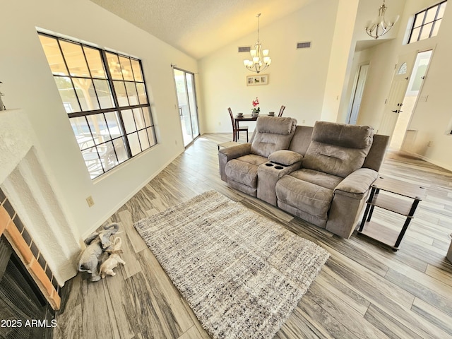 living room with hardwood / wood-style floors, a textured ceiling, high vaulted ceiling, and a chandelier