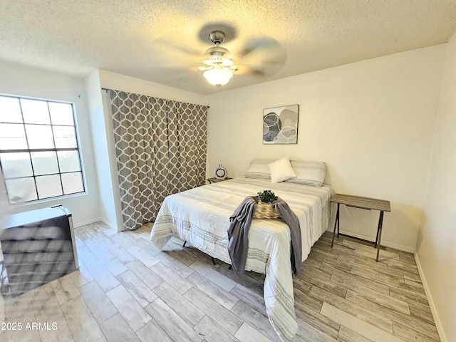 bedroom with ceiling fan, a textured ceiling, and light wood-type flooring