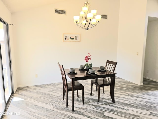 dining space featuring hardwood / wood-style flooring, lofted ceiling, and a chandelier