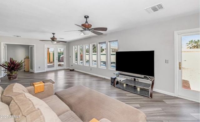 living area with wood finished floors, visible vents, and baseboards