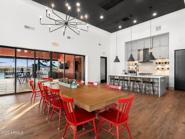dining area with a towering ceiling, dark wood-type flooring, and a chandelier