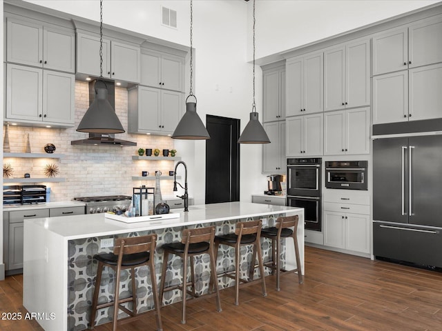 kitchen with built in fridge, multiple ovens, custom exhaust hood, gray cabinets, and light countertops